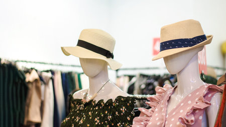 Two mannequins showcase stylish hats amidst colorful clothing in a retail setting, highlighting contemporary fashion trends.の写真素材