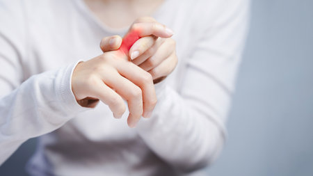 Close up of woman pressing finger joint with visible redness showing pain inflammation or arthritis in hand joint care concept.の写真素材