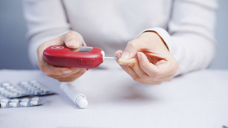 A blood glucose meter diabetes test hand finger red close up healthcare medical device white...