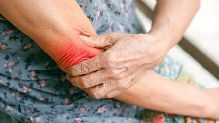 Close up of elderly woman holding painful red swollen elbow indicating joint inflammation arthritis...