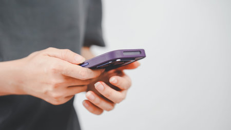 Close-up of a person holding a smartphone with a purple case, focusing on hand gesture in a modern...