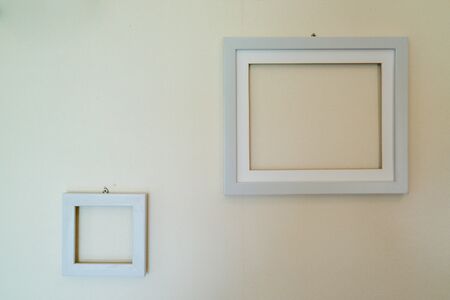 Empty wooden picture frames mounted on the wall with wallpaper behind.