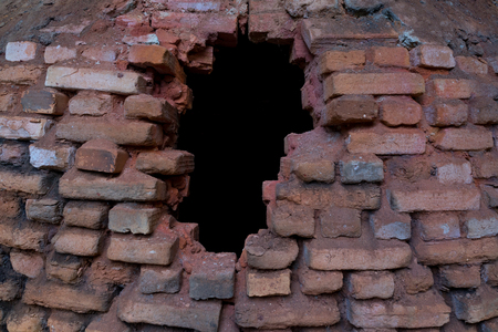 Black hole in the old red brick stove covered with dust and ashes.の写真素材
