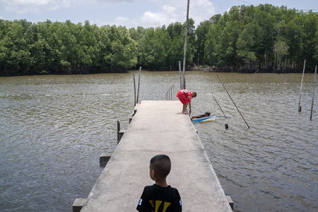 Chantaburi Thailand  April 18 2015: Unidentified kids playing on the concrete pier near the river and mangrove forest.のeditorial素材