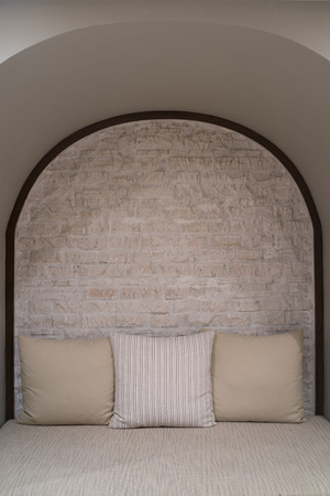 Cloth sofa with brown pillows against brick wall.の写真素材