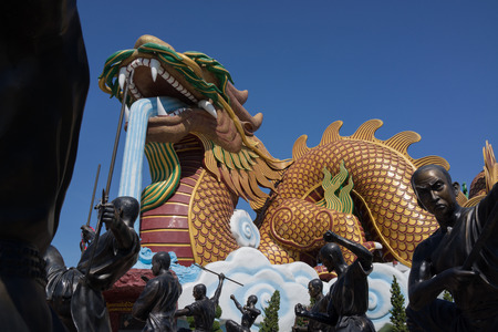 Suphanburi, Thailand - November 30, 2015: Statues of giant Chinese dragon and Shaolin monks in kungfu actions stand in front of the museum.のeditorial素材
