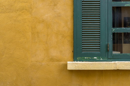 Green wooden window on yellow wall.の写真素材