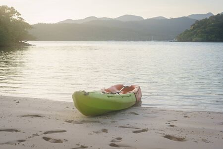 Green and orange kayak on sand beach near Salakphet bay in Koh Chang island, Thailand.の写真素材