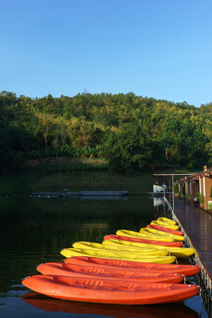 Yellow and red kayaks with green forest and clear blue sky background.のeditorial素材
