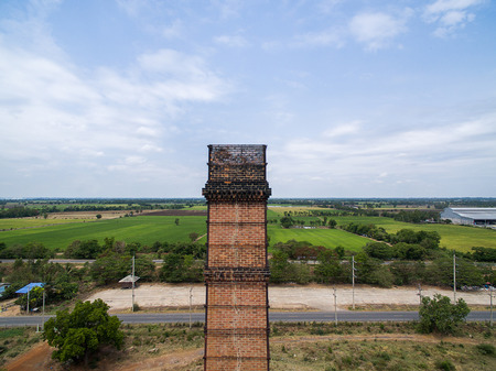 Old red brick smokestack with rice farms in the backgroundの写真素材