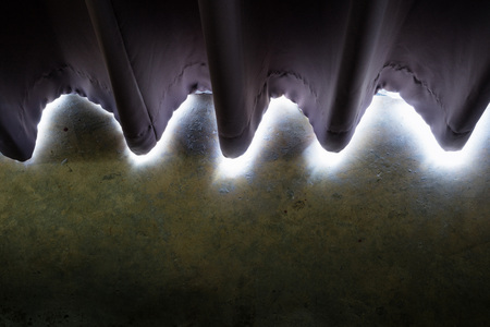 Abstract of white light through edges of dark purple curtain and concrete floor.の写真素材