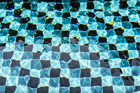Black and blue mosaic floor tile of swimming pool in daylight.の写真素材