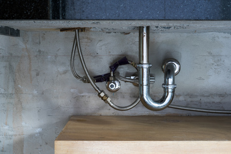 Bathroom stainless steel sink pipes, trap and drain on concrete wall.の写真素材