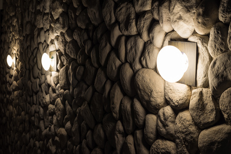 Round wall lamps on dark old stone wall at night.の写真素材