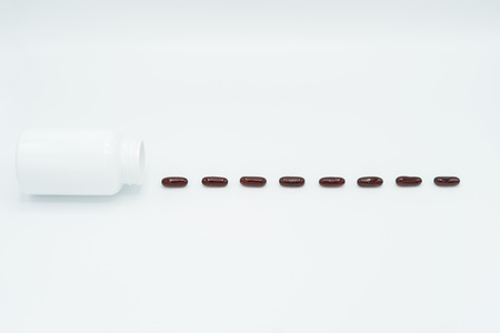 Dashed line of black capsules and white bottle on white background.の写真素材