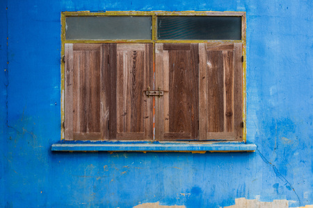 Closed wooden windows with yellow frame on old blue concrete wallの写真素材