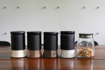 Glass jars of coffee, creamer, sugar, cocoa and thai snack on wooden table.の写真素材