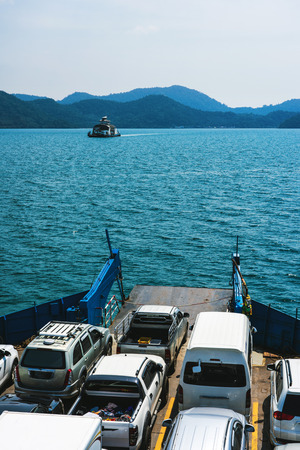 Car ferries carrying automobiles to an island across blue sea.の写真素材