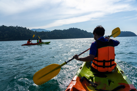 Asian teenagers and woman paddling on red and green kayaks.の写真素材