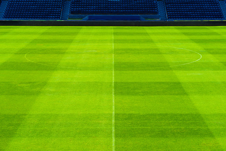 Center circle of green grass soccer field with rows of blue seats.
