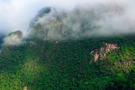 White mist and clouds over green limestone mountain in the morning light in Khao Sok National Park...