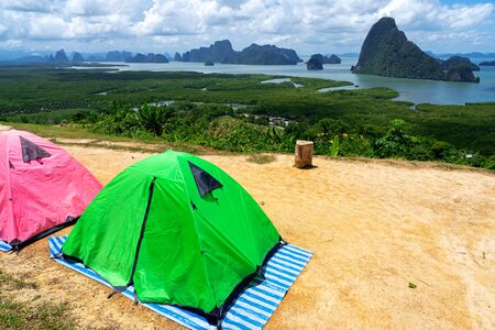 Green and pink tents on campsite with sea and small islands view of Phang Nga Bay in Thailand.の写真素材