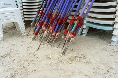 Stacks of unused plastic beach chairs and purple wooden beach umbrellas on empty sand beach in Pattaya, Thailand due to the downfall of tourism during  pandemic.の写真素材