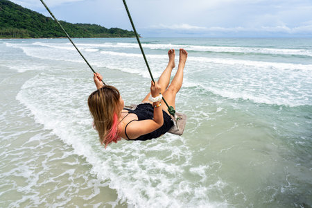 Asian female adult playing on beach swing with sea waves and blue sky background on Koh Kood island in Trat,Thailand.の写真素材