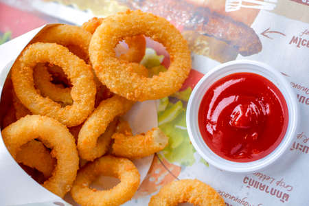 Fast food crunchy fried onion rings in breading close-up, top viewの写真素材