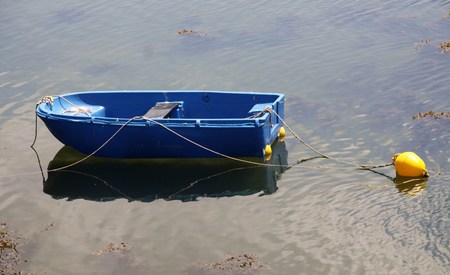 blue rowboat quietly lying on the water with yellow buoyの写真素材