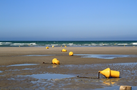 Beach at low tide with yellow buoysの写真素材