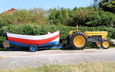 Yellow tractor pulling a trailer on a colorful old wooden boatの写真素材