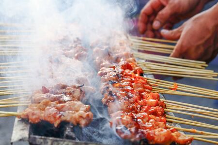 Satay cooked at street market over charcoal smokingの写真素材