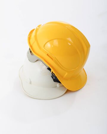 Yellow and white safety helmets stacked on white background