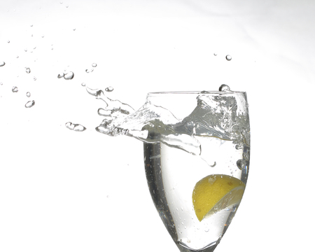 Splashing liquid water from glass with lime on white backgroundの写真素材