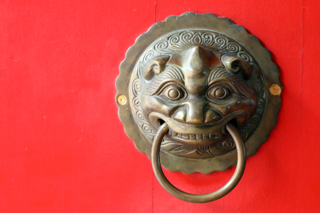 Metal Chinese Lion Head door knocker on red wooden door の写真素材