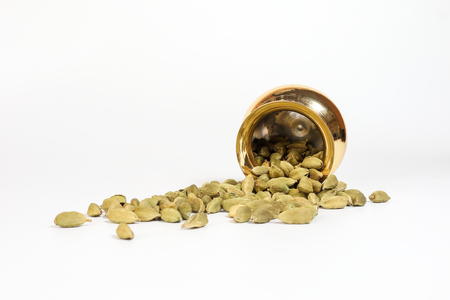 Cardamom  spice in shiny metal pot brass copper golden on white background の写真素材