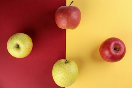 Red yellow green apple on yellow red colour paper background copy space for textの写真素材