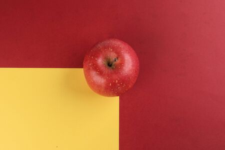 Red apple on yellow red colour paper background copy space for text