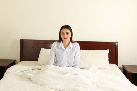Young beautiful modern Malay woman relax morning wake up on bed look at cameraの写真素材