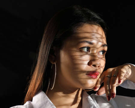Young beautiful modern Malay woman background with gobo cast shadow on face