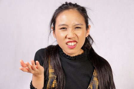 Young attractive southeast Asian woman posing facial expression question what why irritatedの写真素材