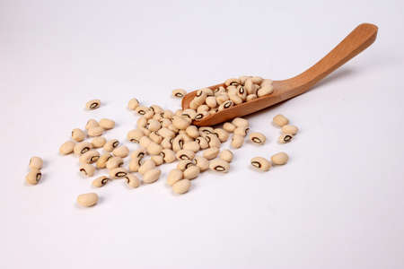 Blackeye beans in wooden scoop spoon on white background