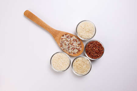 Long grain basmati medium grain jasmine short grain pilaf polau risotto brown low glycaemic index gi rice in small glass bowl wooden spoon on white background copy text space top flat lay viewの写真素材