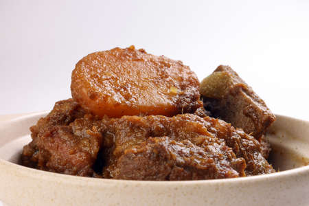 Asian style Beef bhuna dry curry with potato in ceramic bowl over white backgroundの写真素材