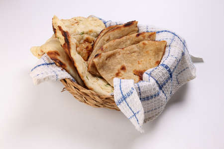 Asian bread chapati naan tandoori paratha bread in checkered cloths basket over white backgroundの写真素材