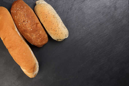 Freshly baked bread loaf bun roll round long mix verity copy text space border frame black backgroundの写真素材