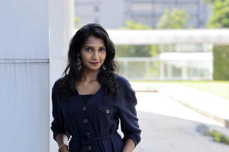 Young attractive beautiful Indian woman in dark blue formal jumpsuit look forward confidently...