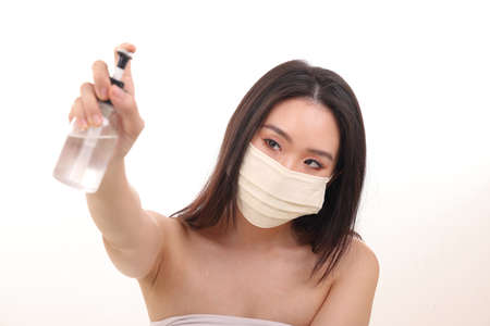 Beautiful young south east Asian woman three ply anti virus surgical face mask posing holding using...