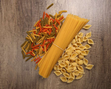 dry raw spaghetti conchiglie seashells fusilli cork screw color pasta variety on rustic wood backgroundの写真素材